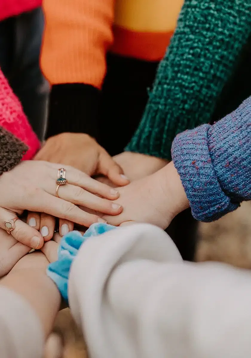 a group of teens all put their hands together to illustrate group therapy at a day treatment program | Oasis Ascent